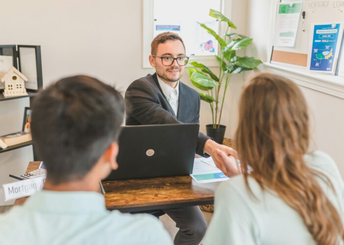 A mortgage broker meeting clients in an office, discussing agreements and loans.