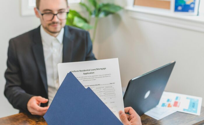 Mortgage broker and client discussing loan application with documents on table.